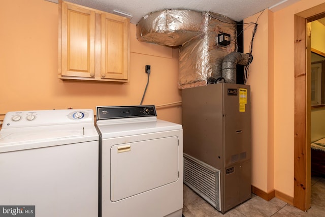 washroom with light tile patterned floors, a textured ceiling, separate washer and dryer, cabinet space, and heating unit