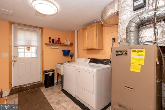 washroom featuring a sink, cabinet space, a textured ceiling, and independent washer and dryer