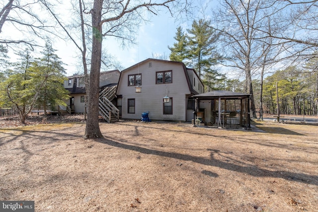 back of property with stairs, a gazebo, and a gambrel roof