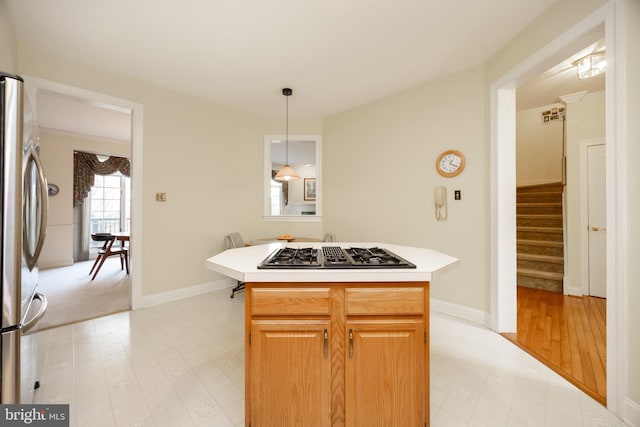 kitchen featuring gas cooktop, light countertops, hanging light fixtures, freestanding refrigerator, and light floors