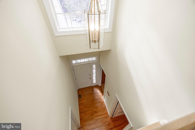 entryway featuring a towering ceiling, wood-type flooring, a chandelier, and baseboards