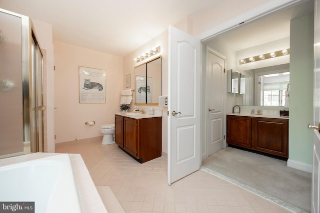 bathroom with toilet, a stall shower, baseboards, and two vanities