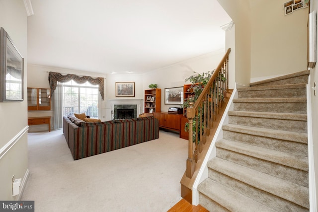 living area featuring baseboards, stairway, a high end fireplace, and light colored carpet