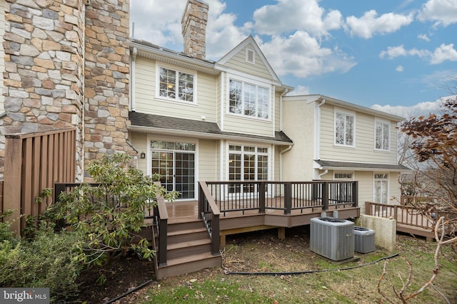 rear view of property with a deck, central AC, a shingled roof, and a chimney