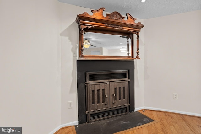 interior details featuring a fireplace, a textured ceiling, baseboards, and wood finished floors