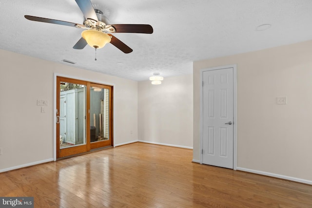 spare room featuring baseboards, visible vents, ceiling fan, a textured ceiling, and light wood-type flooring