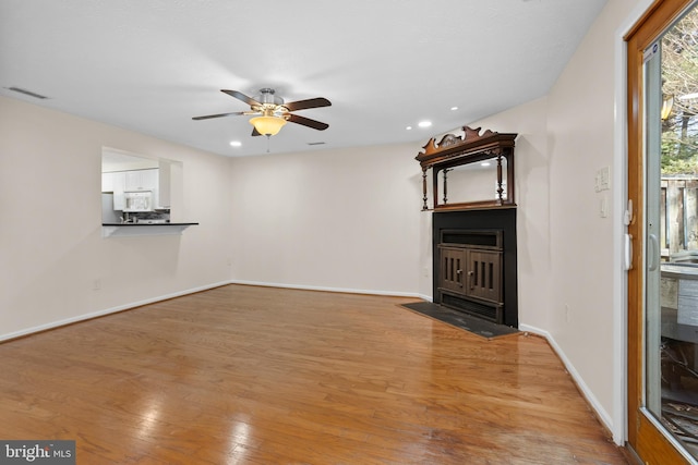 unfurnished living room with light wood finished floors, a ceiling fan, visible vents, and baseboards