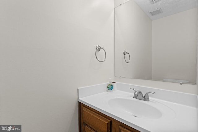 bathroom featuring visible vents, a textured ceiling, and vanity