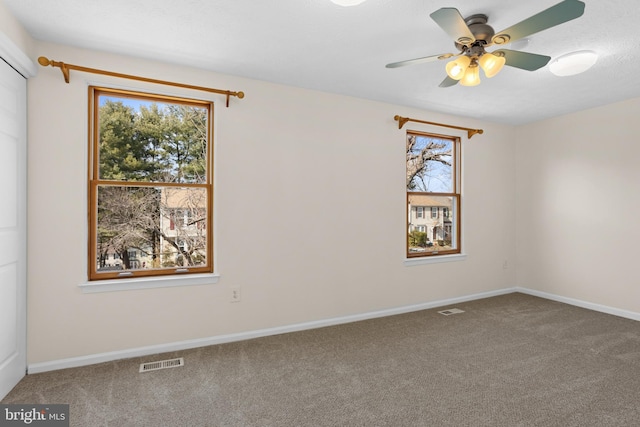 empty room with a ceiling fan, carpet, visible vents, and baseboards