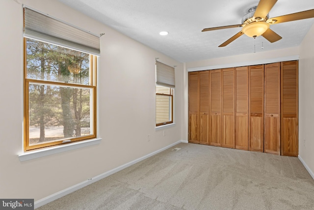 unfurnished bedroom featuring recessed lighting, a closet, light colored carpet, a ceiling fan, and baseboards