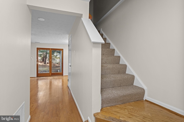 staircase with visible vents, baseboards, and wood finished floors