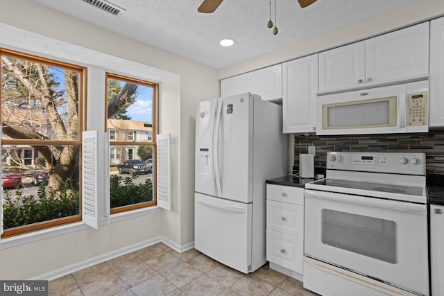 kitchen featuring white appliances, visible vents, decorative backsplash, dark countertops, and white cabinetry