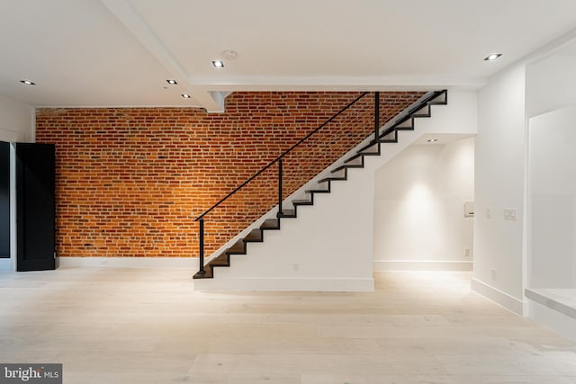 staircase featuring baseboards, brick wall, wood finished floors, and recessed lighting