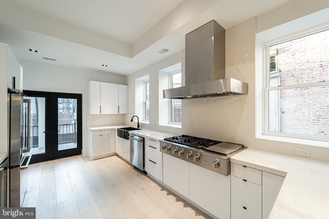 kitchen featuring stainless steel appliances, tasteful backsplash, visible vents, light wood-style flooring, and wall chimney exhaust hood