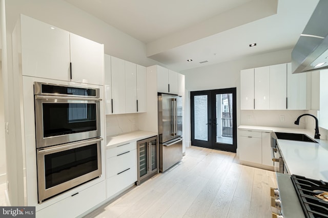 kitchen featuring wine cooler, stainless steel appliances, a sink, light countertops, and backsplash