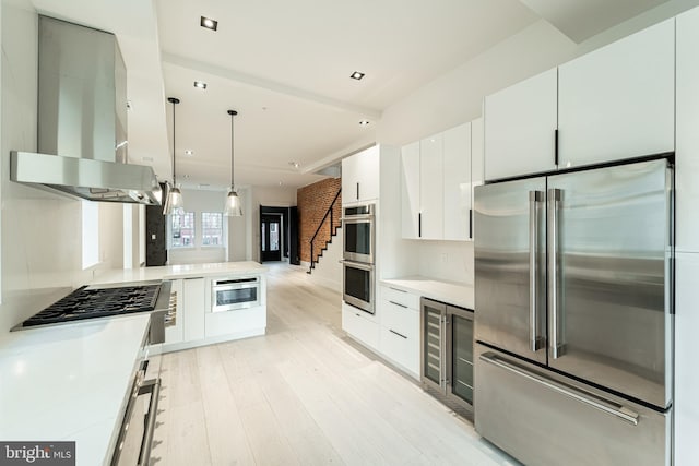 kitchen featuring island exhaust hood, light wood finished floors, stainless steel appliances, light countertops, and white cabinetry