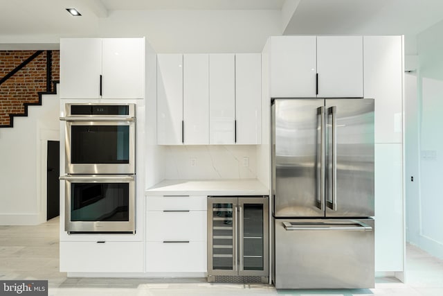 kitchen with white cabinets, beverage cooler, stainless steel appliances, and light countertops