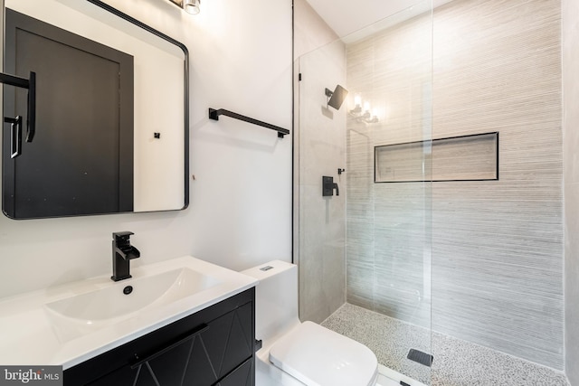 full bathroom featuring toilet, tiled shower, and vanity