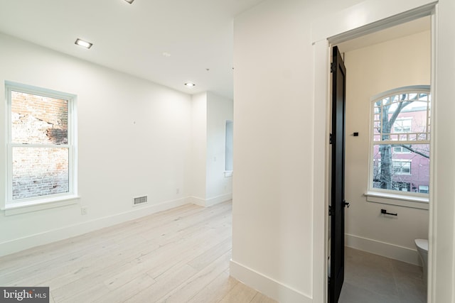 interior space featuring light wood-style floors, baseboards, and visible vents