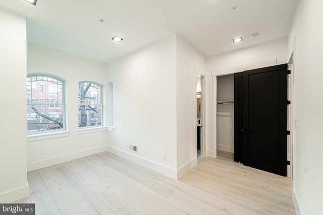 empty room with light wood-style floors, visible vents, baseboards, and recessed lighting