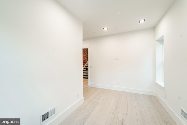 spare room with baseboards, visible vents, light wood finished floors, and stairs