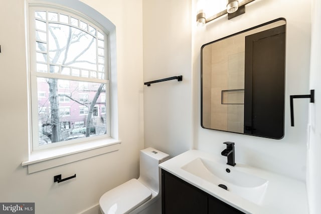 bathroom with toilet, vanity, and a wealth of natural light