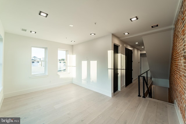 empty room with recessed lighting, visible vents, brick wall, light wood-type flooring, and baseboards