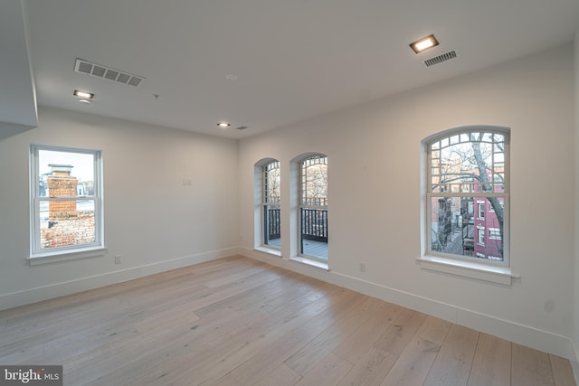 empty room with light wood finished floors, baseboards, and visible vents