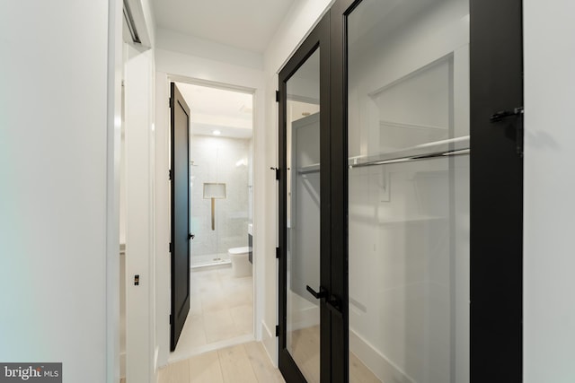 bathroom featuring a stall shower, toilet, and wood finished floors