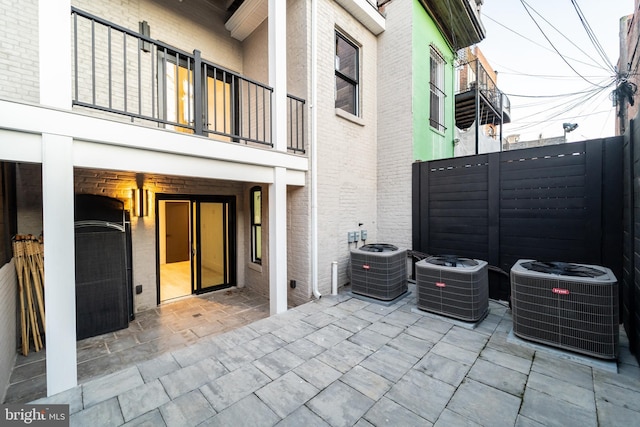 view of patio featuring fence, a balcony, and central air condition unit