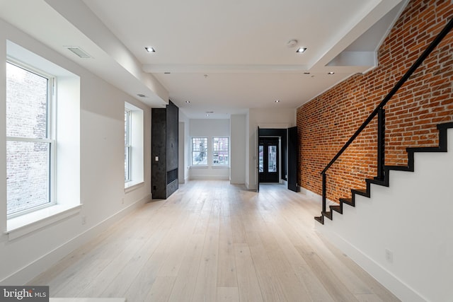 foyer featuring brick wall, visible vents, baseboards, stairs, and hardwood / wood-style floors