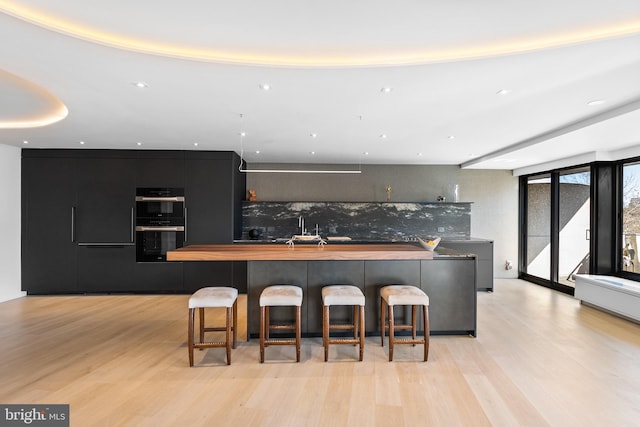 2510 Virginia Ave NW Unit 512-S, Washington, DC 20037 - kitchen featuring modern cabinets, light wood-style floors, a breakfast bar area, and decorative backsplash