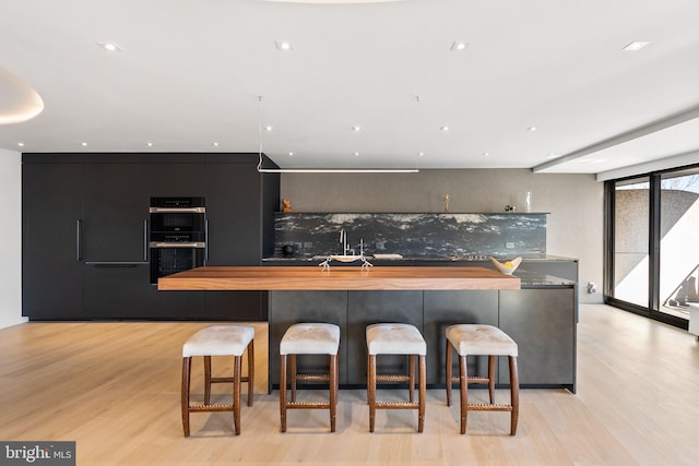 2510 Virginia Ave NW Unit 512-S, Washington, DC 20037 - kitchen with light wood-style flooring, a kitchen bar, wood counters, and tasteful backsplash