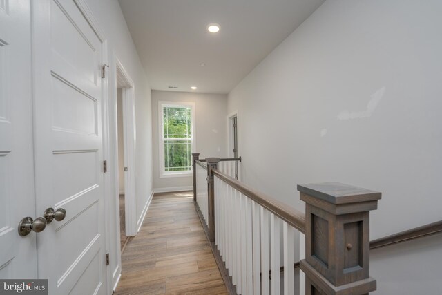 hall featuring baseboards, light wood-style flooring, an upstairs landing, and recessed lighting