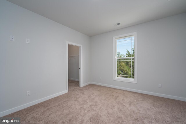 unfurnished room with carpet, visible vents, and baseboards