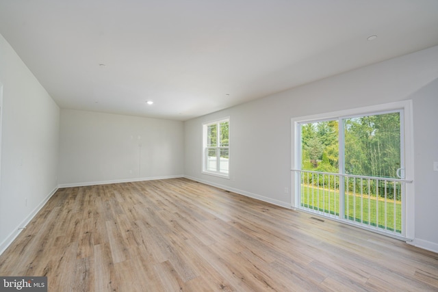 spare room featuring light wood-style floors, visible vents, and baseboards