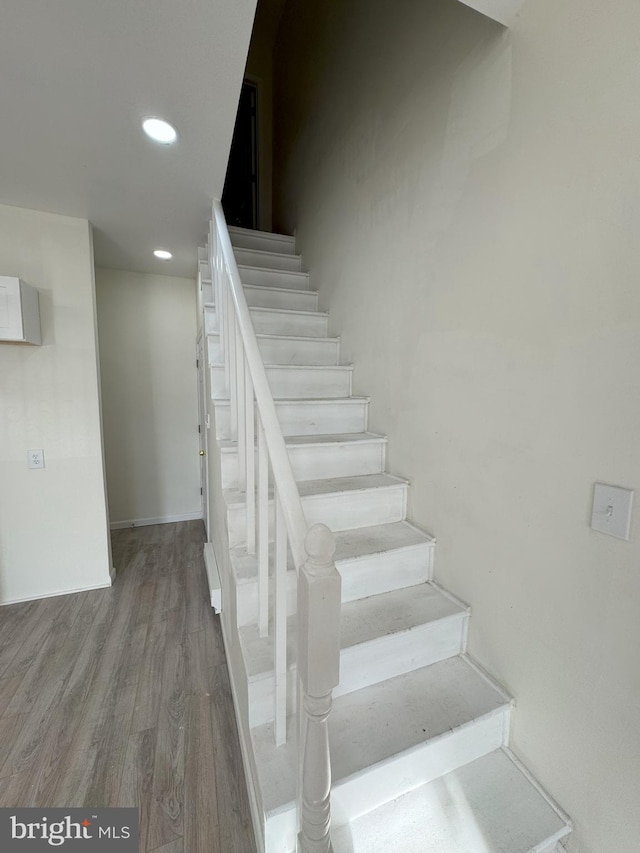 stairs with baseboards, wood finished floors, and recessed lighting