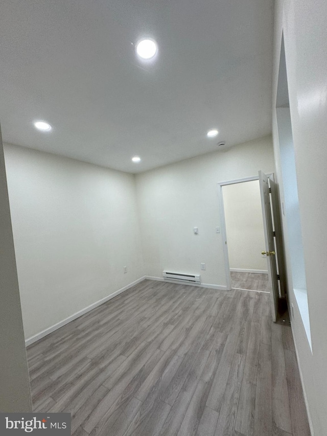 basement featuring baseboards, a baseboard heating unit, wood finished floors, and recessed lighting