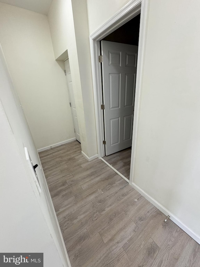 hallway with baseboards and wood finished floors