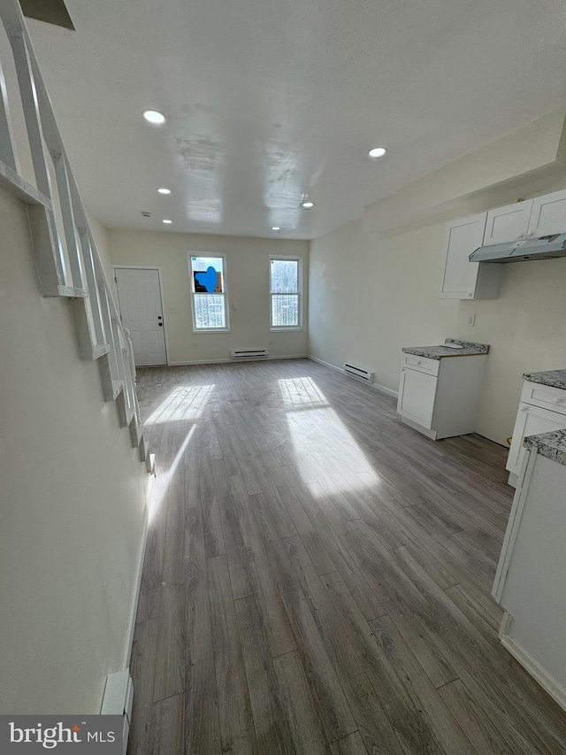 unfurnished living room featuring a baseboard heating unit, recessed lighting, wood finished floors, and baseboards