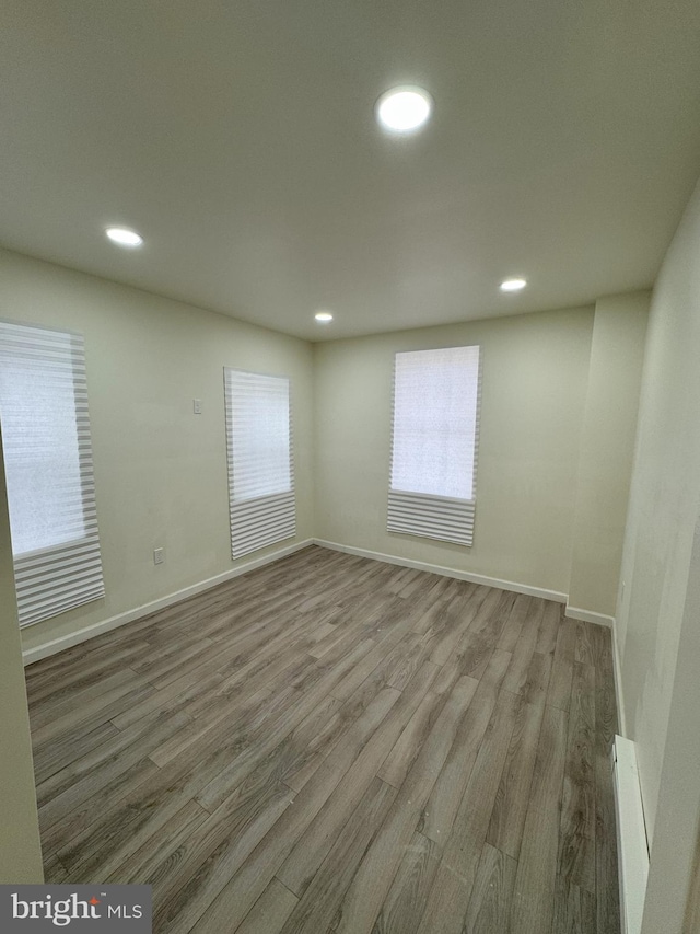 unfurnished room featuring baseboards, wood finished floors, and recessed lighting