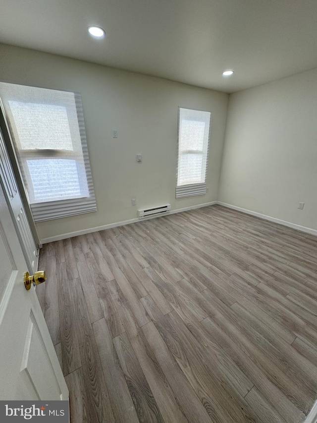 unfurnished room featuring recessed lighting, baseboards, baseboard heating, and wood finished floors