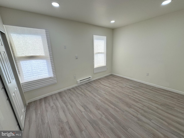 spare room with light wood-type flooring, baseboards, a baseboard heating unit, and recessed lighting