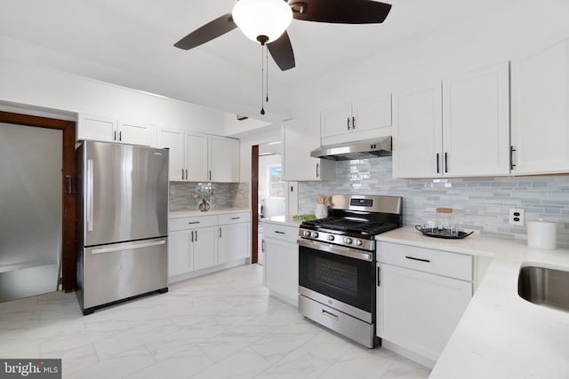 kitchen with under cabinet range hood, white cabinetry, marble finish floor, and stainless steel appliances