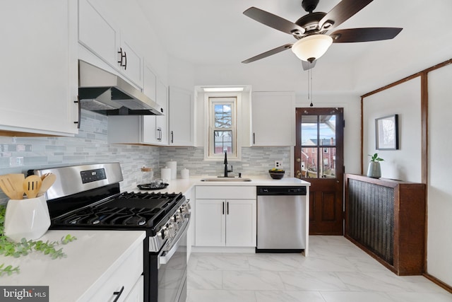 kitchen with marble finish floor, stainless steel appliances, light countertops, a sink, and under cabinet range hood