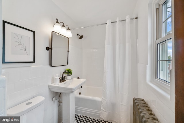 full bath featuring toilet, tile walls, wainscoting, radiator, and shower / bath combination with curtain