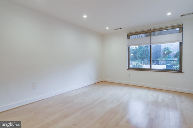 unfurnished room featuring light wood-type flooring, visible vents, baseboards, and recessed lighting