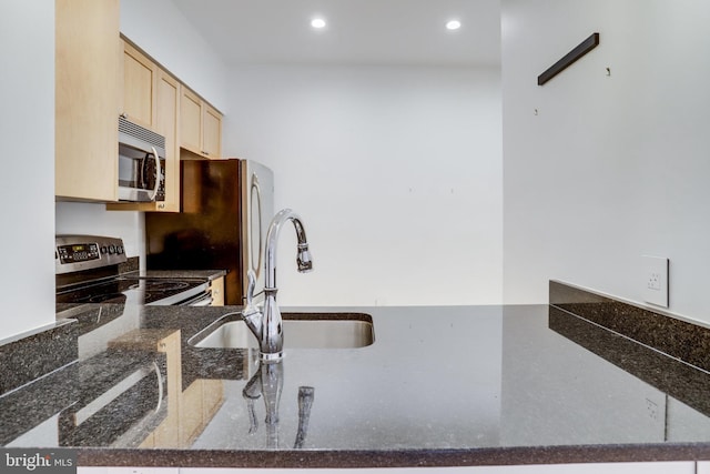 kitchen featuring dark stone countertops, light brown cabinets, recessed lighting, a sink, and stainless steel appliances