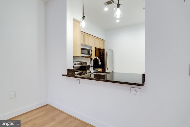 kitchen featuring wood finished floors, baseboards, visible vents, light brown cabinetry, and stainless steel appliances