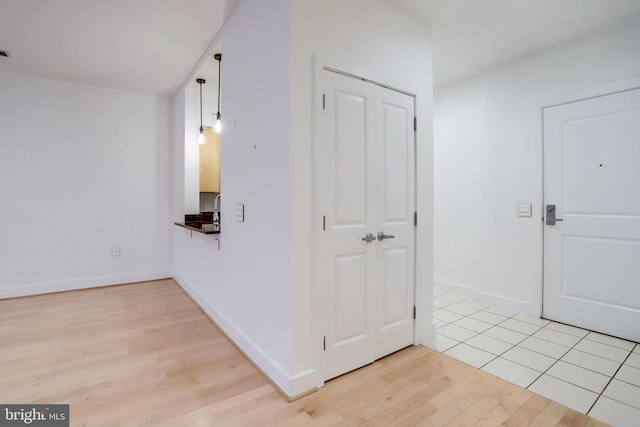 corridor featuring baseboards and light wood-style flooring